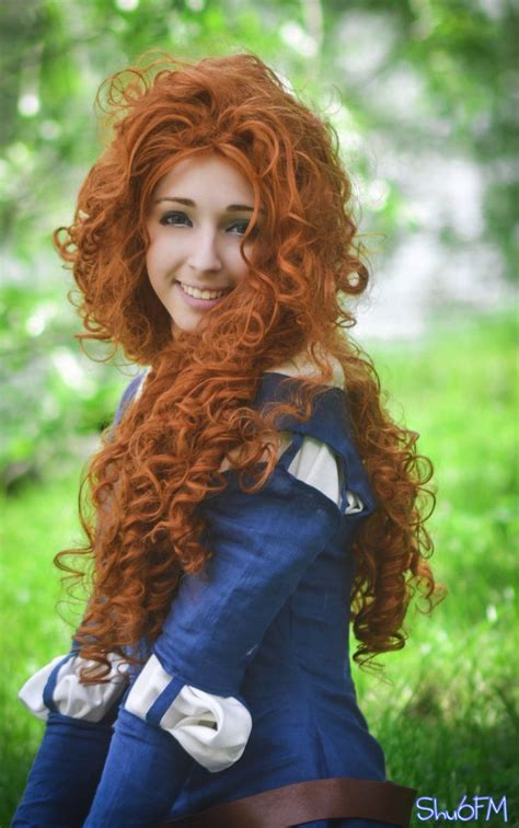 A Woman With Long Red Hair Sitting In The Grass Wearing A Blue Dress