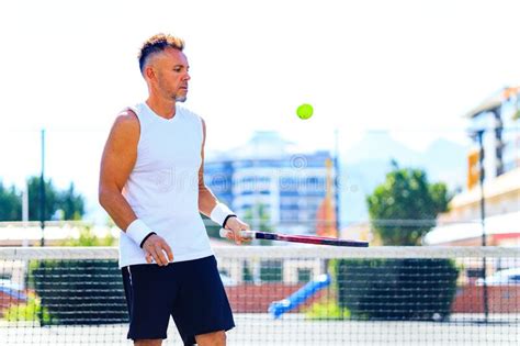 Mature Handsome Man Playing Tennis On Tennis Court At Sunny Day Stock