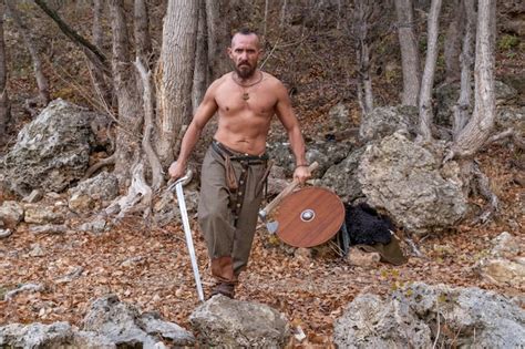 Premium Photo A Bearded Viking With A Naked Torso Holds A Sword In