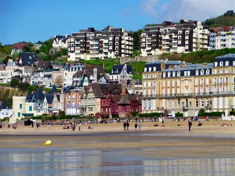 People Are Walking On The Beach In Front Of Some Buildings