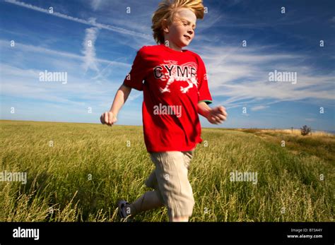 Young Boy Running Through A Field Of Grass In A Cymru T Shirt Stock