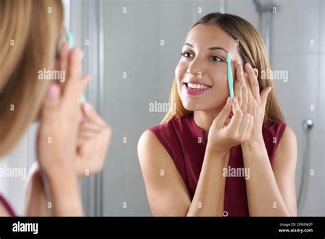 Beautiful Young Woman Shaving Her Eyebrows By Razor On The Mirror At