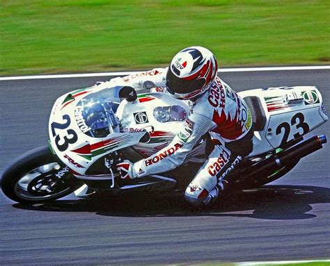 A Man Riding A Motorcycle On Top Of A Race Track With Grass In The