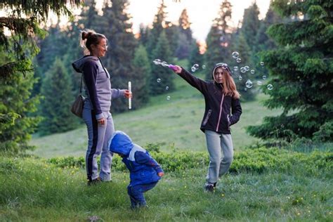 Madre juega con su hija y su hijo en pompas de jabón en un bosque