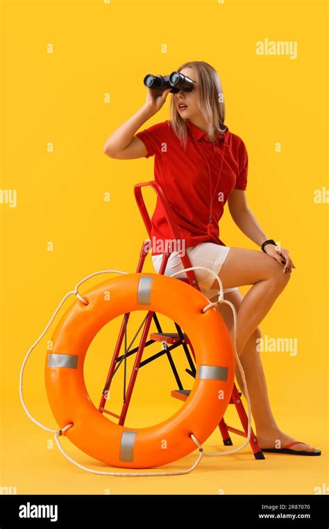 Female Lifeguard With Binoculars And Ring Buoy Sitting On Yellow