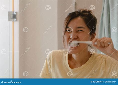 Asian Thai Woman Holding Toothbrush And Brushing Teeth Looking At The