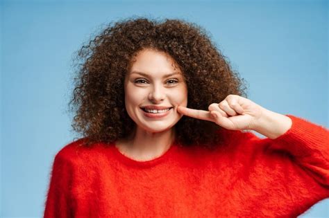 Premium Photo Beautiful Smiling Body Positive Woman With Curly Hair Pointing Fingers At Teeth