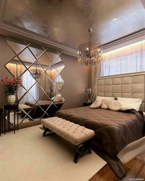 A Bed Room With A Neatly Made Bed And A Mirror On The Wall Above It