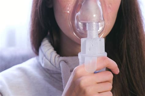 Use nebulizer and inhaler for the treatment. Young woman inhaling ...