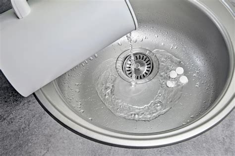 Premium Photo Hot Water Is Poured From A White Electric Kettle Into A Metal Kitchen Sink With