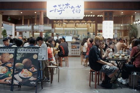 People eating at a busy food court with signs. photo – Free Image on