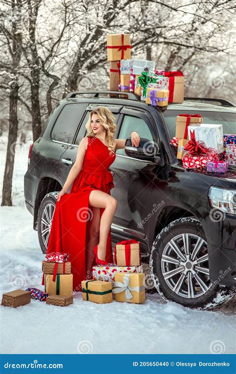 Fille Blonde Luxueuse Dans Une Robe Rouge Avec Des Cadeaux à Côté D une Grosse Voiture Noire