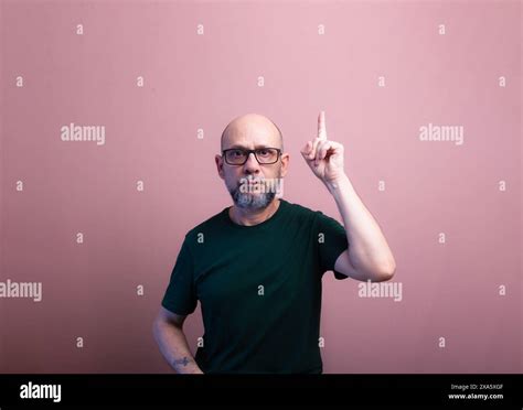 Bearded Bald Man With Prescription Glasses Pointing Up With His Finger