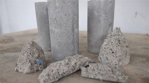 Three Cement Vases Sitting On Top Of A Table Next To Some Rocks And Pebbles