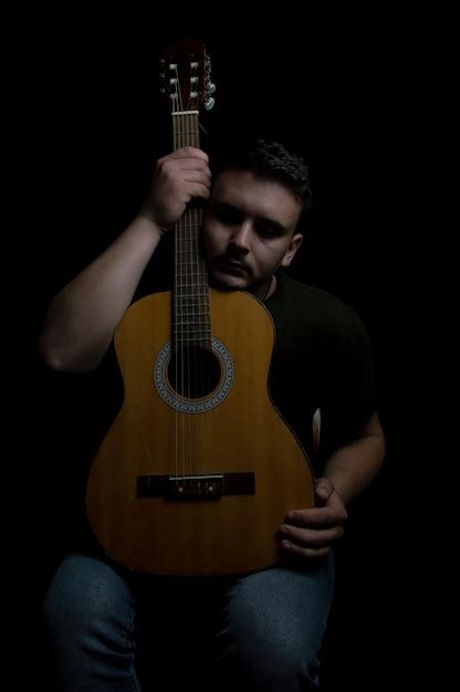 Premium Photo Midsection Of Man Holding Guitar Against Black Background