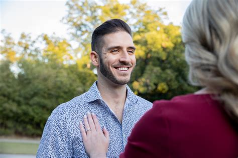 Woman Places Hand With Engagement Ring On Fiances Chest While Standing