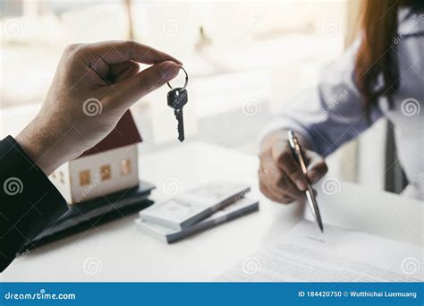 Hand Of Real Estate Agent Passes The Key To New Homeowners In Office With Buyer House Concept