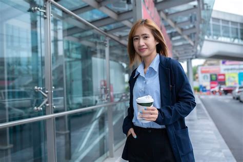 Hermosa mujer yendo a trabajar con café caminando cerca del edificio de