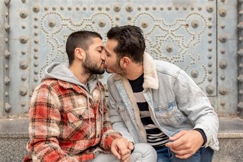 Una pareja gay enamorada se sienta al aire libre besándose Foto Premium