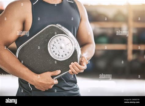 Hand Of A Fit Man Holding A Scale Strong Man Measuring His Weight At The Gym Bodybuilder