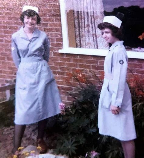 Two Women Standing Next To Each Other In Front Of A Brick Wall And