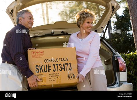 Mature Couple Removing A Cardboard Box From A Car Stock Photo Alamy