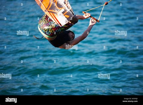 A Young Man Wearing A Helmut And Lifejacket Wakeboarding On A Lake