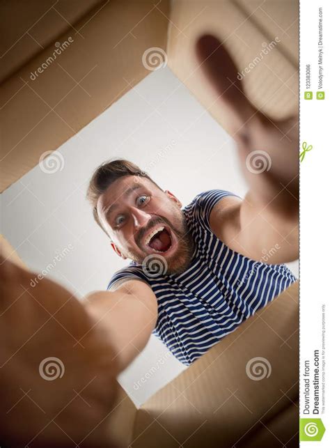 Man Unpacking And Opening Carton Box And Looking Inside Stock Photo