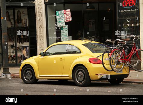 Yellow Volkswagen Beetle In The City With Bicycles On Bike Rack Stock