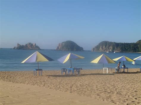 several umbrellas and chairs are on the beach near the water, with two ...