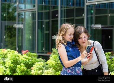 Nice Content Blonde Girl Smiling And Showing Photos In Her Photos To Her Mother While Her Mother