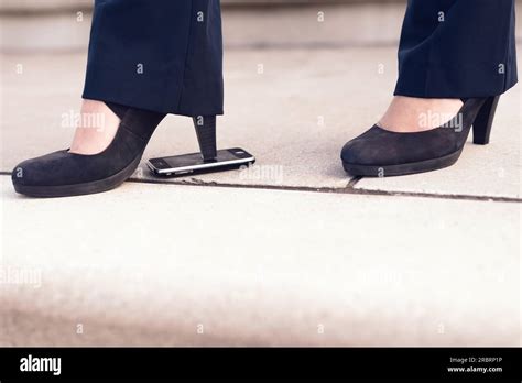 Woman Feet In Black Shoes With Heels Step On Mobile Phone At The Floor