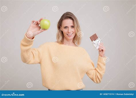 La Belle Jeune Fille Blonde Tient Une Barre De Chocolat Et Une Pomme