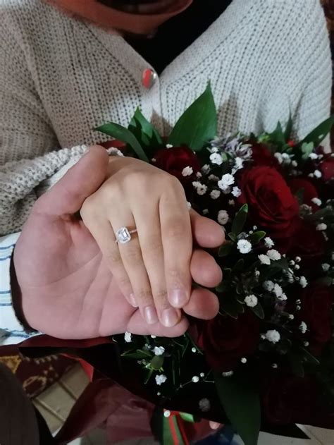 A Man And Woman Holding Hands With Flowers In Front Of Them