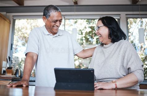 Happy Laughing And Senior Couple With Digital Tablet In A Kitchen