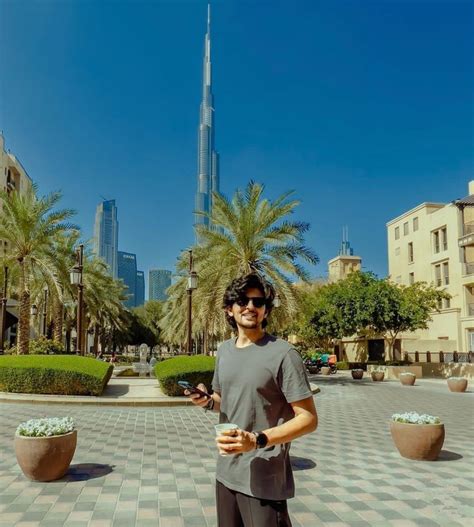 A Man Is Standing In The Middle Of A Courtyard With Palm Trees And