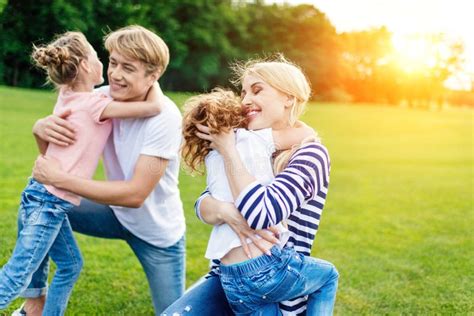 Happy Parents with Two Children Hugging while Resting on Green Meadow ...