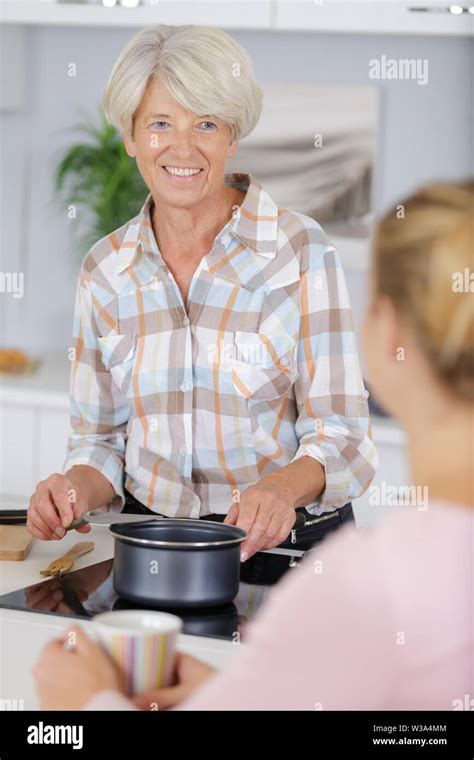 Older Smiling Woman Boiling Water On Kitchen Stove Top Stock Photo Alamy