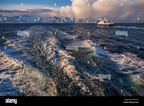 Waves Behind Boat Ship And Snowy Mountain On Horizon With Dramatic Sky