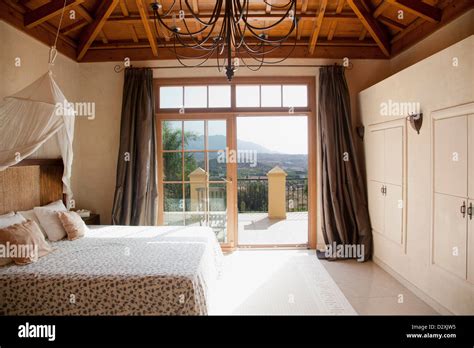 Bed With Canopy And French Doors Leading To Balcony In Bedroom Stock