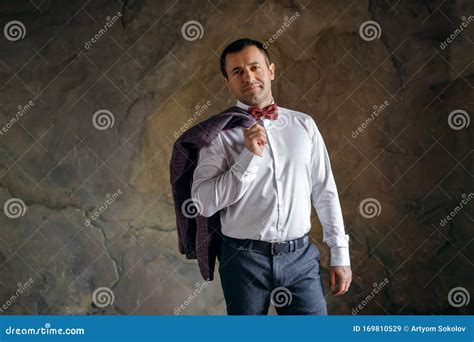 Mature Handsome Man Holding A Jacket Over His Shoulder And Looking At