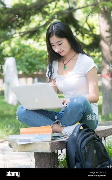 Beautiful Asian College Student With Laptop Sitting On The Campus