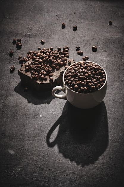 Taza blanca de granos de café tostados recién hechos sobre fondo gris