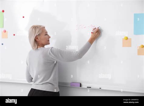 Mature Teacher Writing On Whiteboard In Classroom Stock Photo Alamy