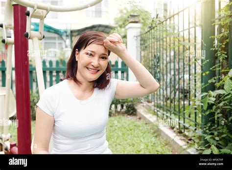 Tired But Smiling Asian Woman Wiping Off Sweat From Her Forehead After