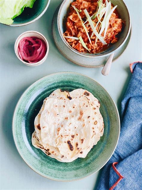 Two Plates Filled With Food On Top Of A Blue Table Cloth Next To Bowls