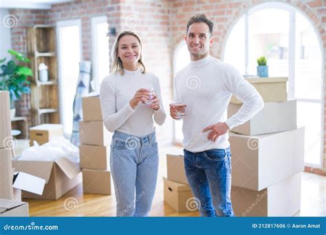 Young Beautiful Couple Standing Drinking Cup Of Coffee At New Home