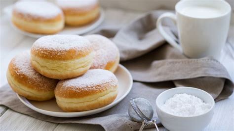 Powdered Sugar Covered Donuts On A White Plate Next To A Cup Of Coffee