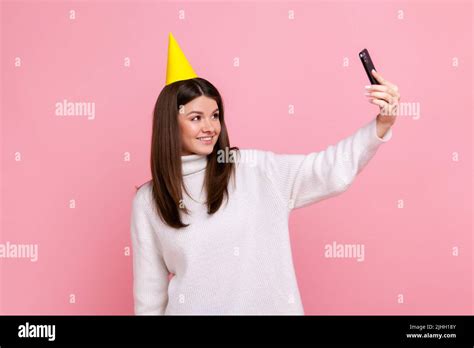 Good Looking Brunette Girl In Party Cone Making Selfie Having Video Call Or Broadcasting