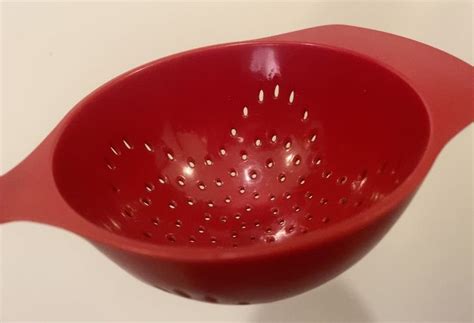 A Red Colander Sitting On Top Of A White Counter